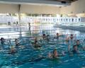 Aqua fitness class in a bright indoor pool, featuring participants immersed in water, focusing on exercise and movement.