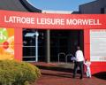 Entrance to Latrobe Leisure Morwell, featuring a bright red sign and a parent with a child approaching the doorway.