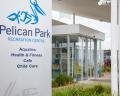 Signage for Pelican Park Recreation Centre, featuring facilities for aquatics, fitness, cafe, and child care. Modern building entrance visible.