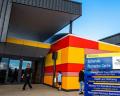 Exterior view of a vibrant, modern building with colorful red and yellow accents, featuring an information sign outside.