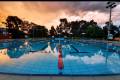 An indoor inground level swimming pool with multiple lanes divided by ropes.