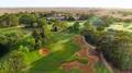 A large green golf course surrounded by trees. 