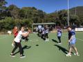 A group of people engaged in a netball training session outdoors, showcasing teamwork and skill development on a sunny day.