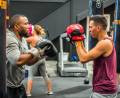 A pair of people, one holding boxing pads the other wearing boxing gloves