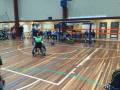 Image of an inside multi use court, with a person in a wheelchair playing football