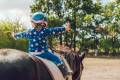 Child on horseback with arms outstretched