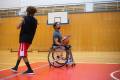 two people playing basketball, one is playing in a wheelchair