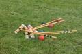 A croquet set laid out on green grass, featuring mallets, balls, and hoops ready for a game