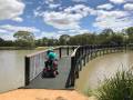 A person in a mobility scooter at the start of Lake Guyatt Footbridge with water