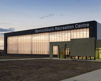 Modern building with large glass windows and a sign reading "International Research Centre," set against a twilight sky.